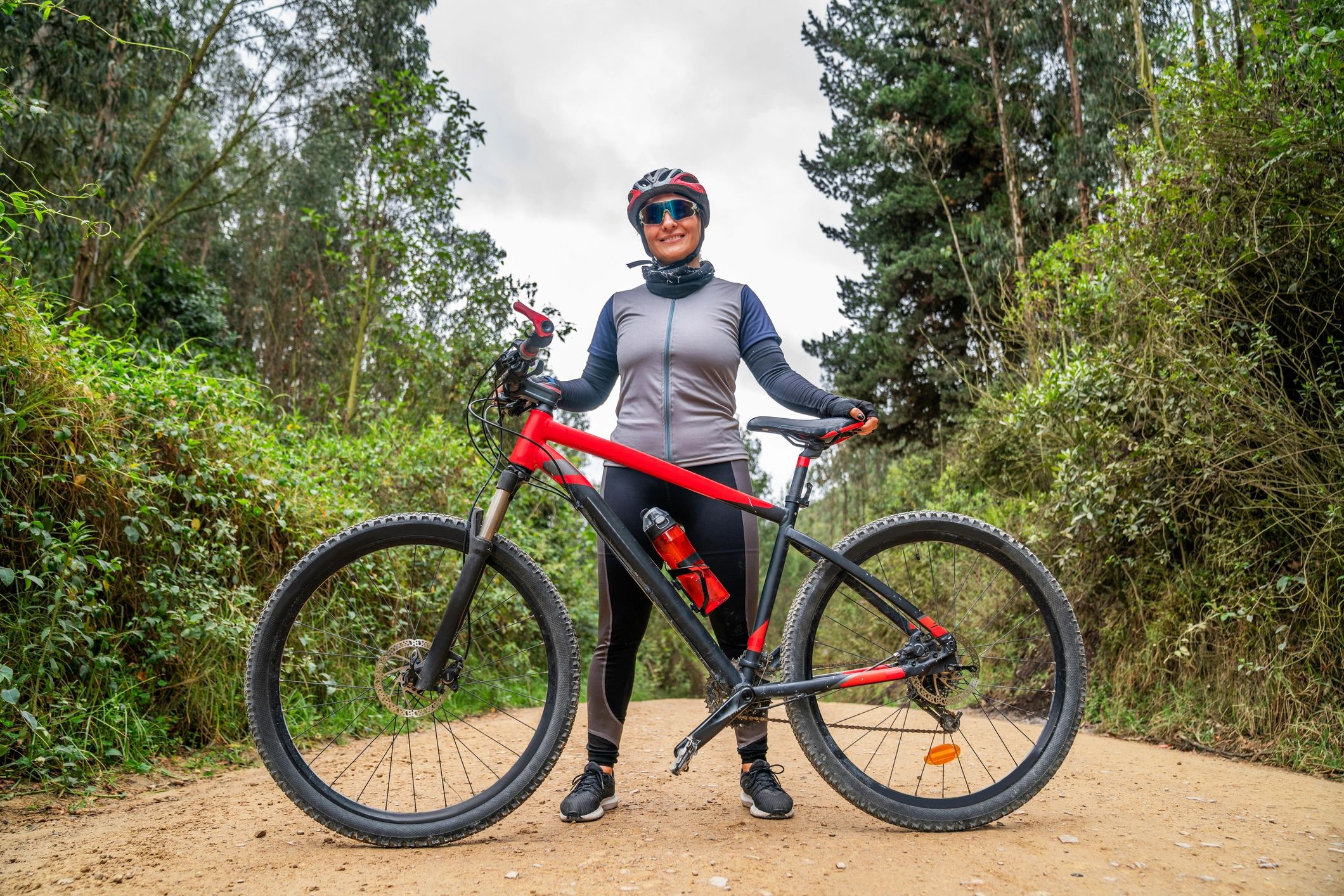Smiling cyclist standing with a mountain bike