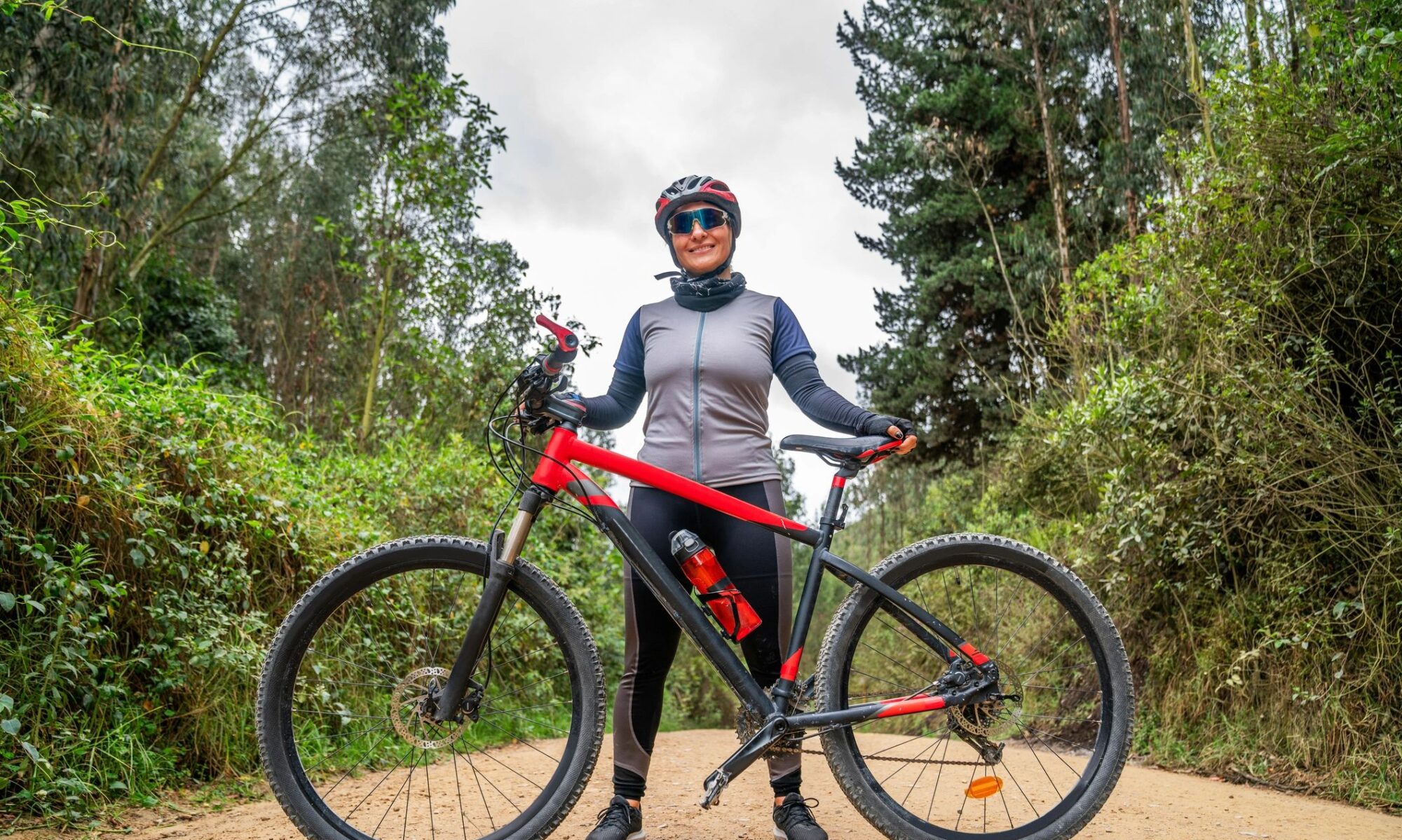 Woman mountain biking and standing next to her bicycle